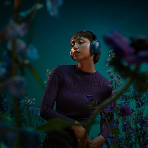 Woman in purple sweater wearing headphones surrounded by flowers.